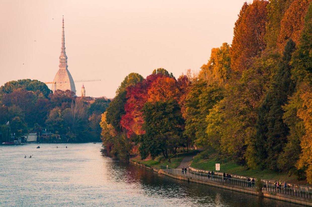 po river in turin city with mole antonelliana and people walking in part