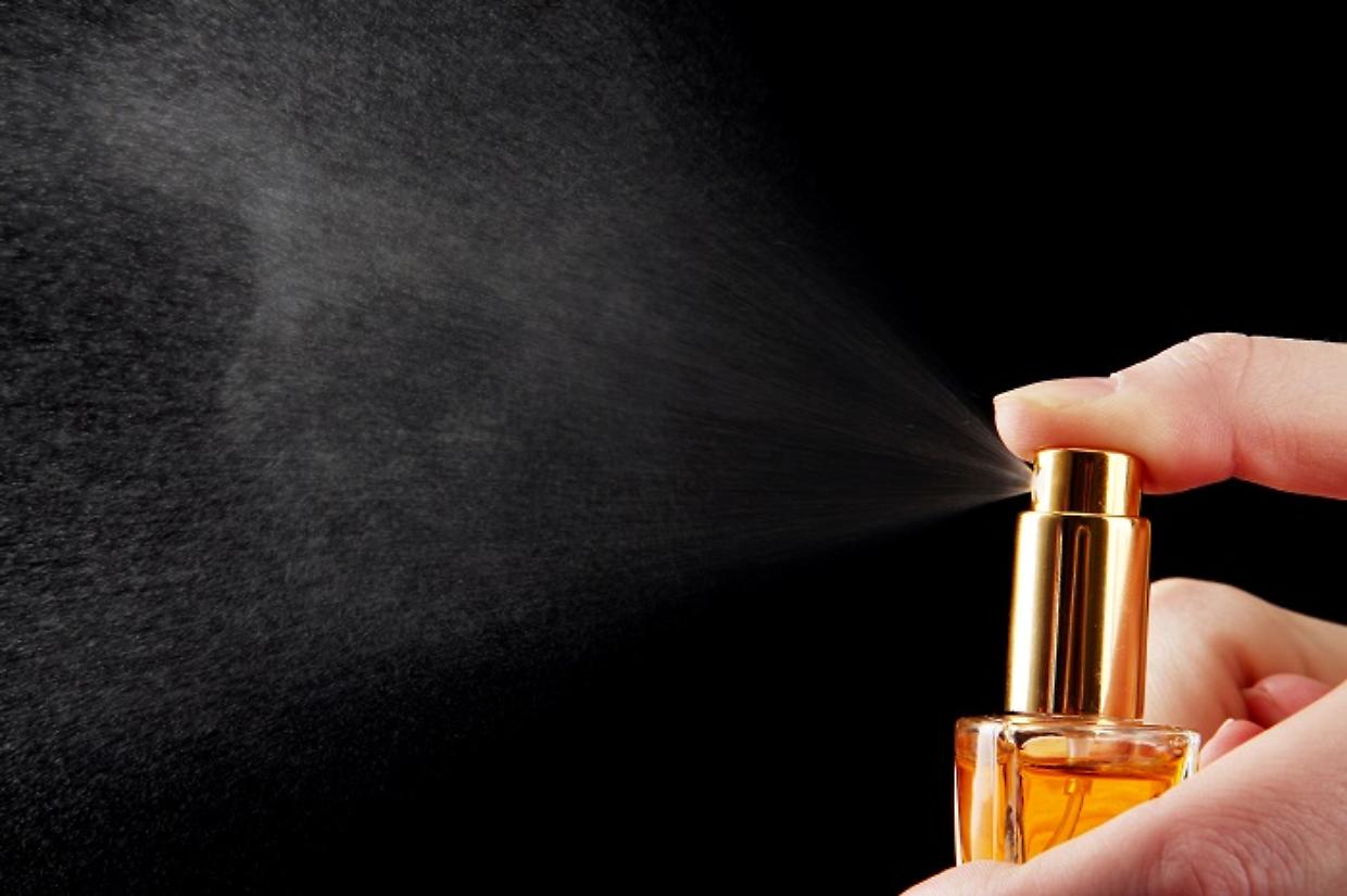 women's perfume in bottle and spraying, on black background