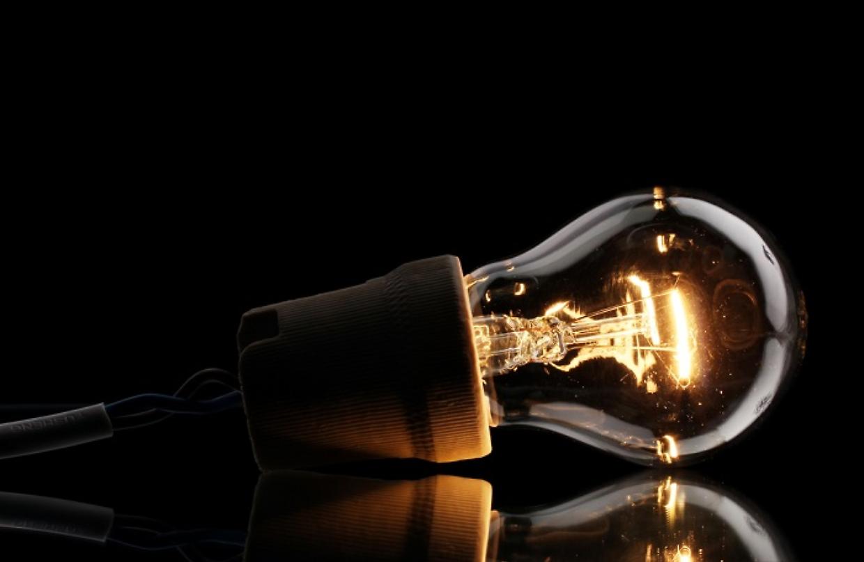 A lit light bulb on black background