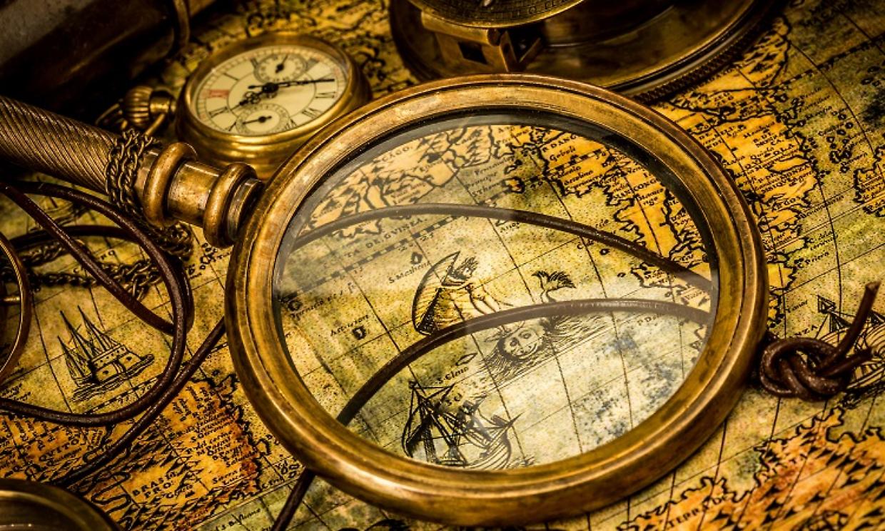 Vintage magnifying glass lies on an ancient world map