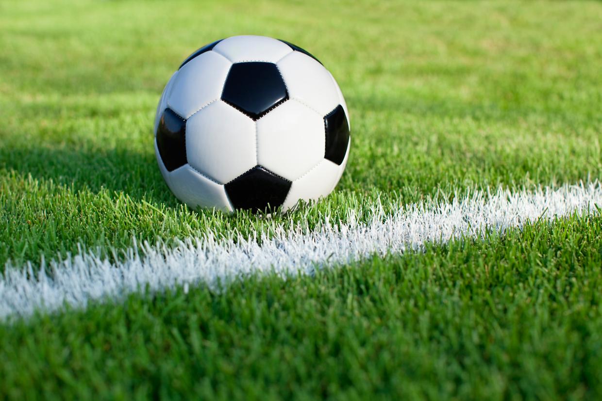 Soccer ball sits on grass field with white stripe