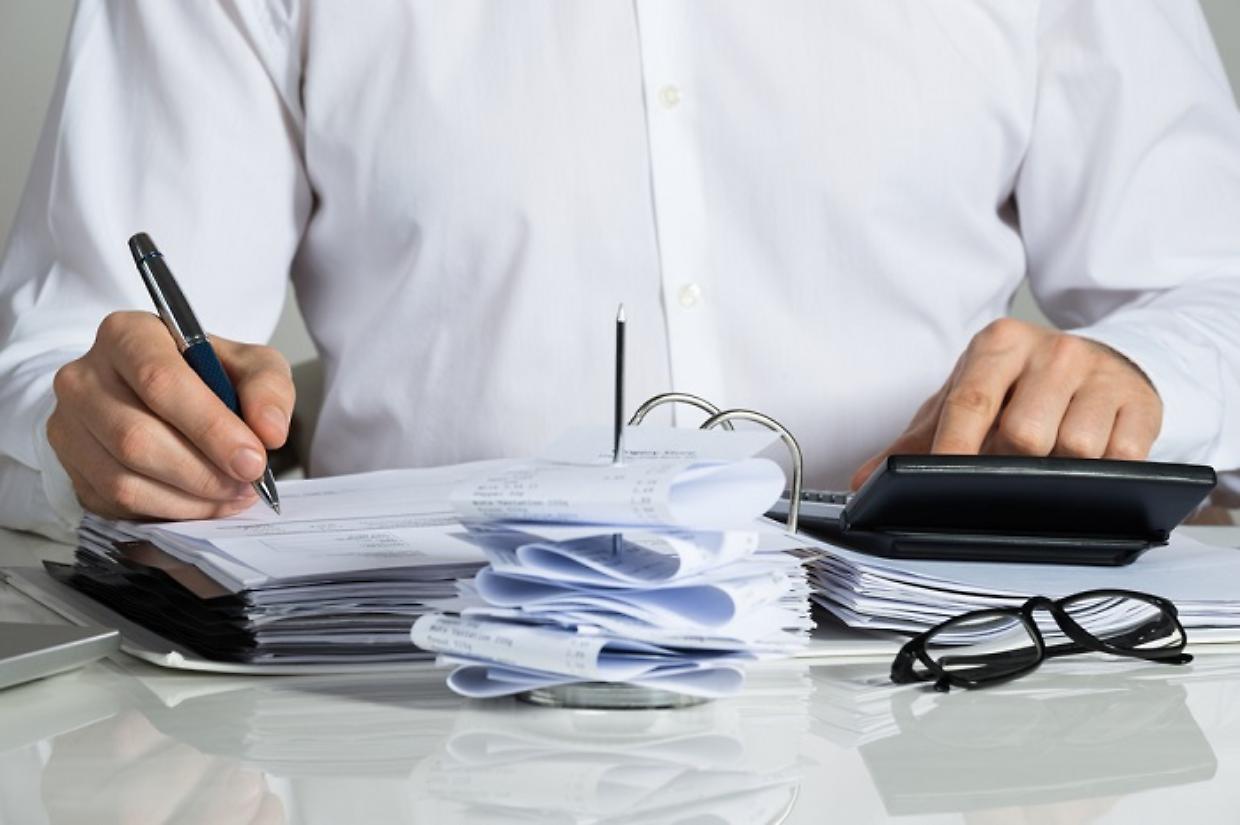 Businessman Calculating Invoice At Desk