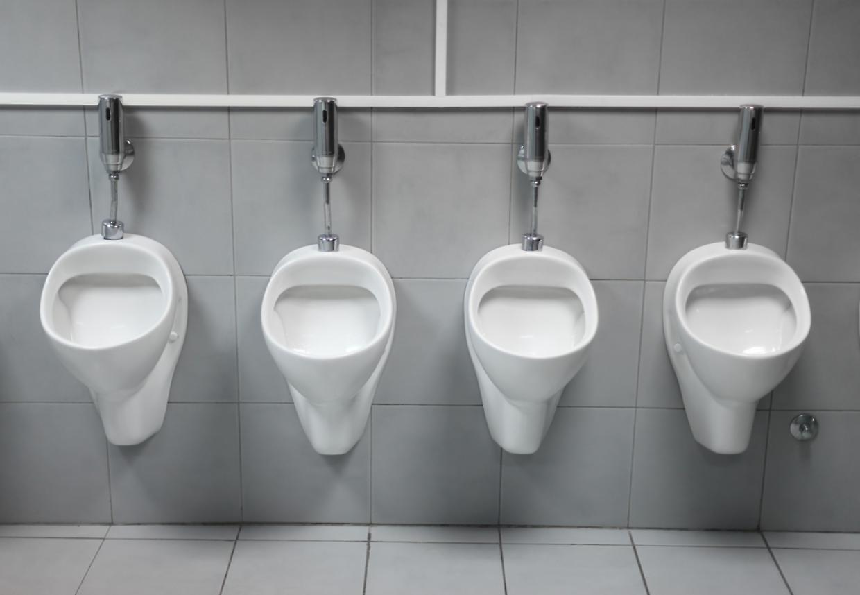 line of white porcelain urinals in public toilets