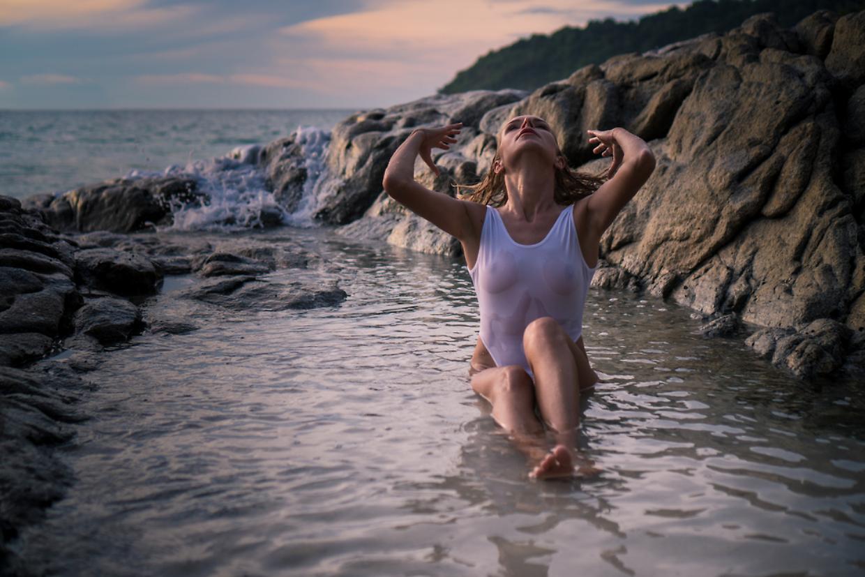 Beautiful woman between rocks on tropical beach