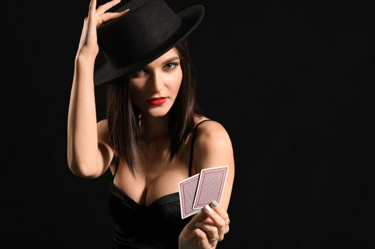Beautiful young woman with playing cards on dark background