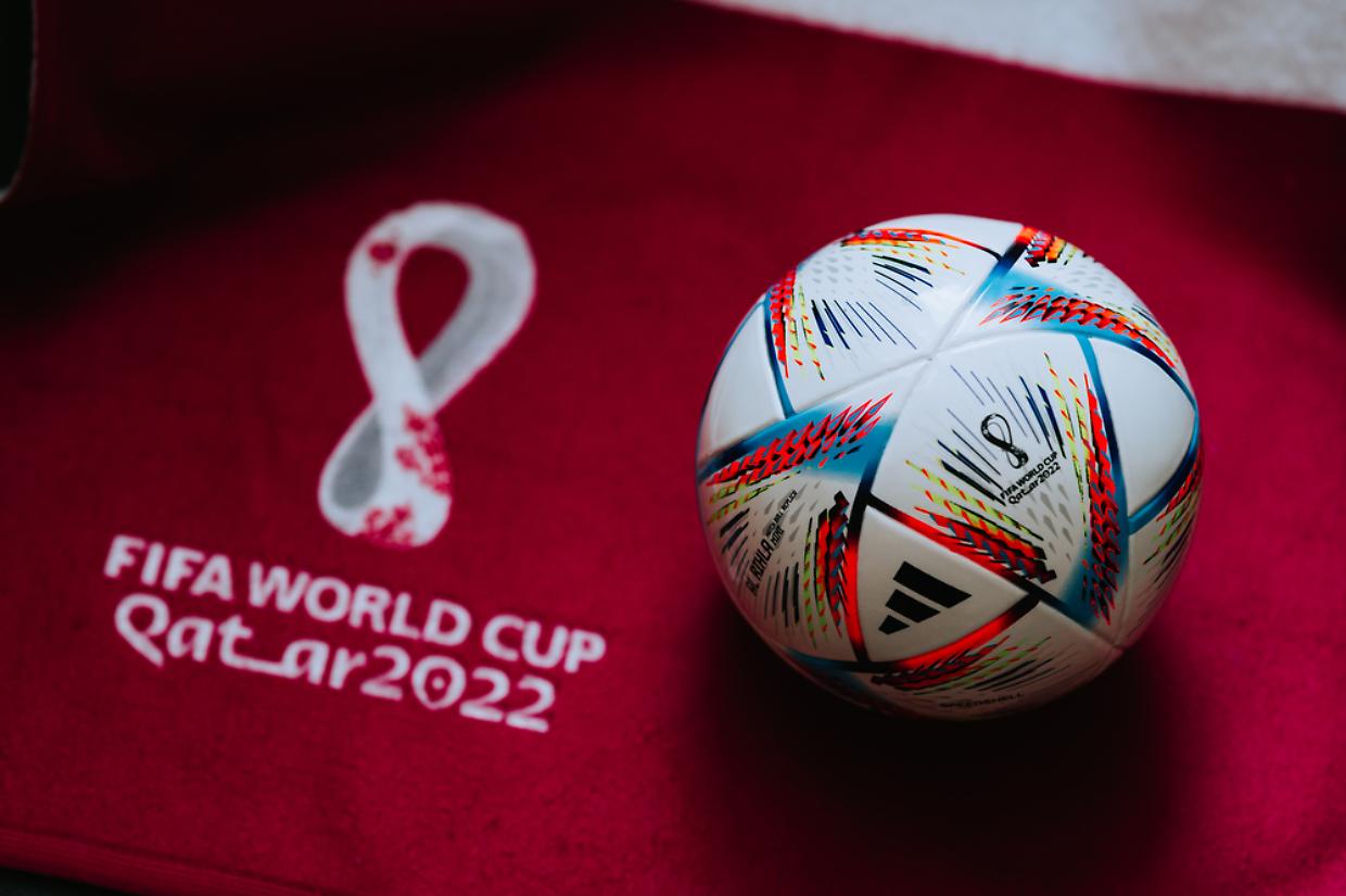 QATAR, DOHA, 18 JULY, 2022: Official Adidas World Cup Football Ball Al Rihla. And logo of FIFA World Cup in Qatar 2022 on red carpet. Soccer sport background, edit space. Qatar 22 Wallpaper.