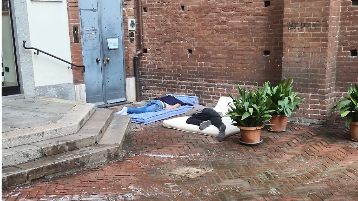 Due uomini dormono davanti alla chiesa di San Domenico