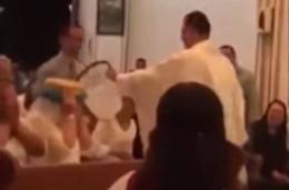 Il parroco burlone: benedice i fedeli con secchiate d'acqua