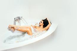 Nuda nella vasca da bagno, sorseggia una coppa di champagne
