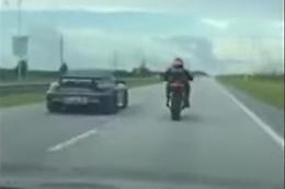 Il motociclista sfida l'auto da corsa, ma finisce male