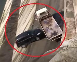 Il carro attrezzi scivola sull'asfalto bagnato, tampona l'auto e la scaraventa giù